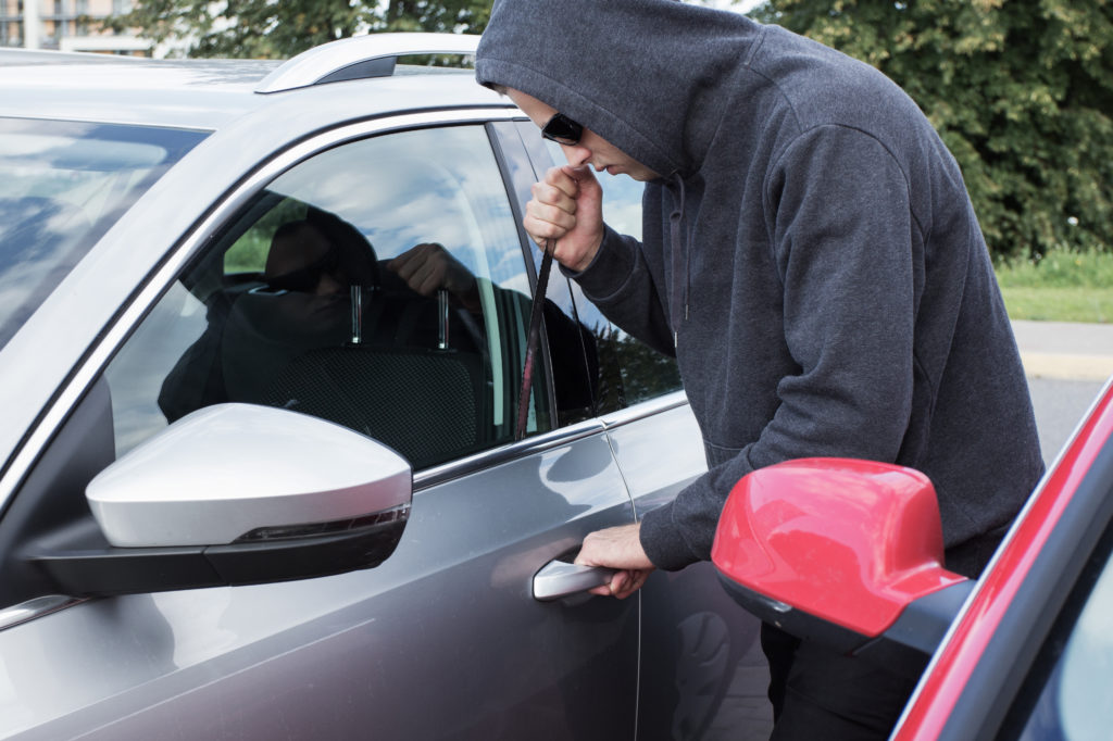 Thief breaking car door lock Thief breaking into a car